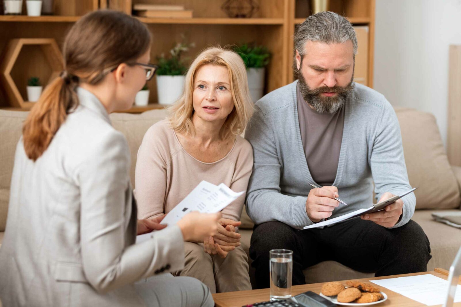 blonde-fraue-berät-ehepaar-während-der-mann-dokumente-liest